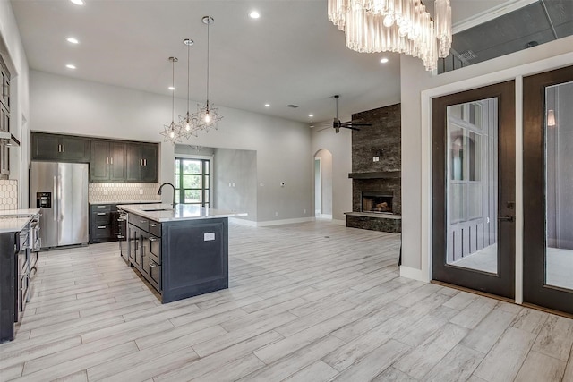 521 Echo Glade Ct, Azle, TX 76020 - kitchen featuring stainless steel refrigerator with ice dispenser, a sink, light countertops, arched walkways, and a chandelier
