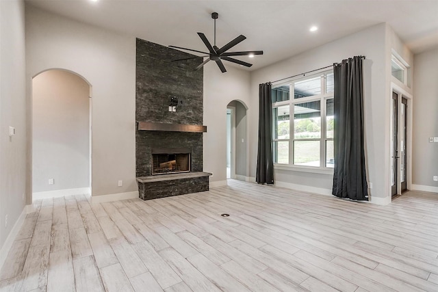 521 Echo Glade Ct, Azle, TX 76020 - unfurnished living room featuring arched walkways, a ceiling fan, wood finished floors, a stone fireplace, and recessed lighting