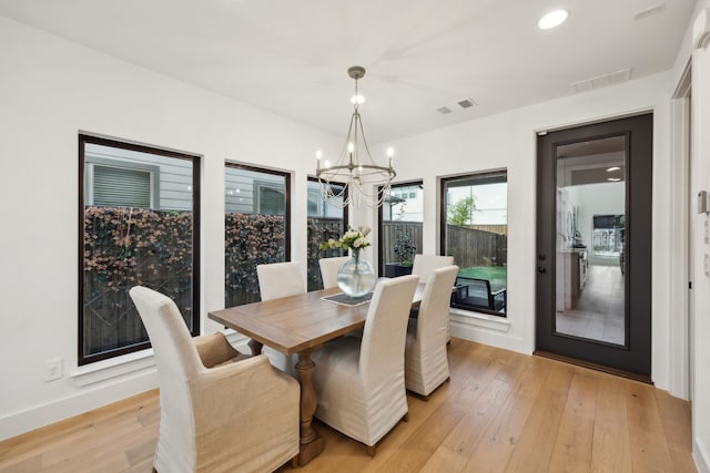 dining space with baseboards, a notable chandelier, light wood-type flooring, and visible vents