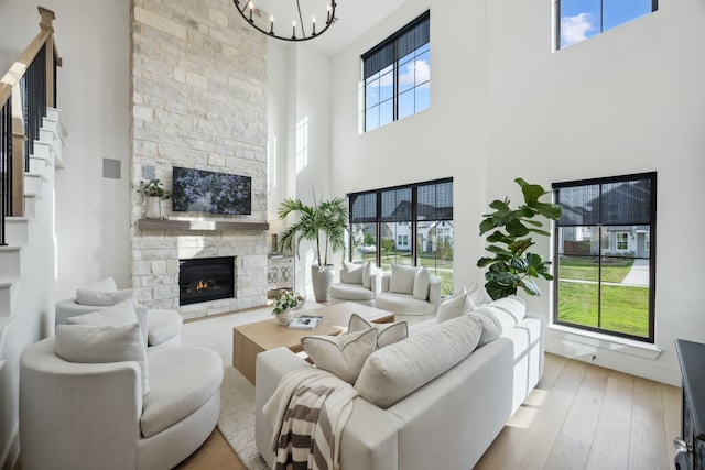 living room featuring wood finished floors, a high ceiling, a notable chandelier, and a fireplace