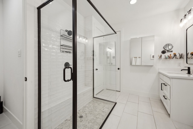 full bath featuring vanity, tile patterned flooring, baseboards, and a stall shower