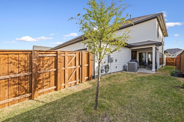 rear view of property featuring central AC, a patio, a fenced backyard, a gate, and a lawn