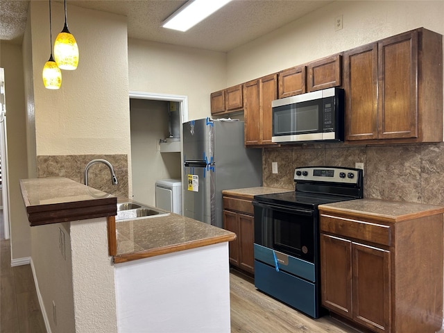 4101 Esters Rd Unit 101, Irving, TX 75038 - kitchen featuring a sink, a textured ceiling, light wood finished floors, stainless steel appliances, and decorative backsplash