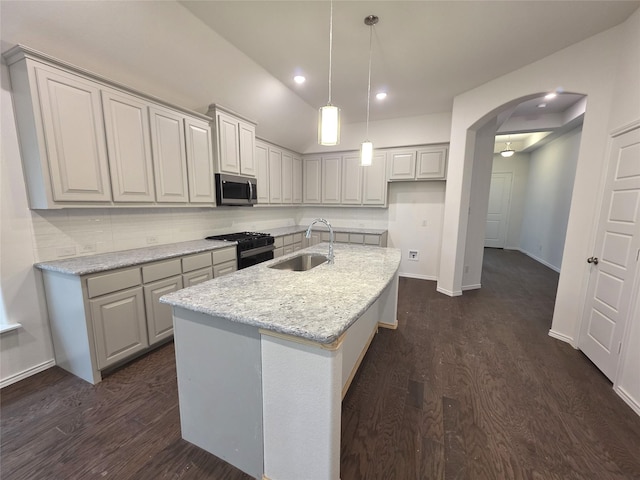 kitchen featuring black gas stove, arched walkways, a sink, stainless steel microwave, and dark wood-style floors