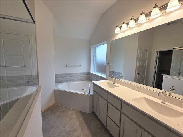 bathroom featuring double vanity, a sink, a bath, and vaulted ceiling