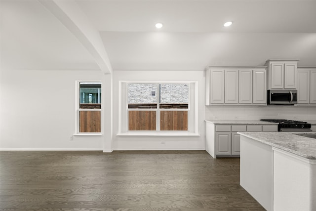 7745 Gatevine Ave, Joshua, TX 76058 - kitchen with stainless steel microwave, gas stove, dark wood-style floors, arched walkways, and tasteful backsplash