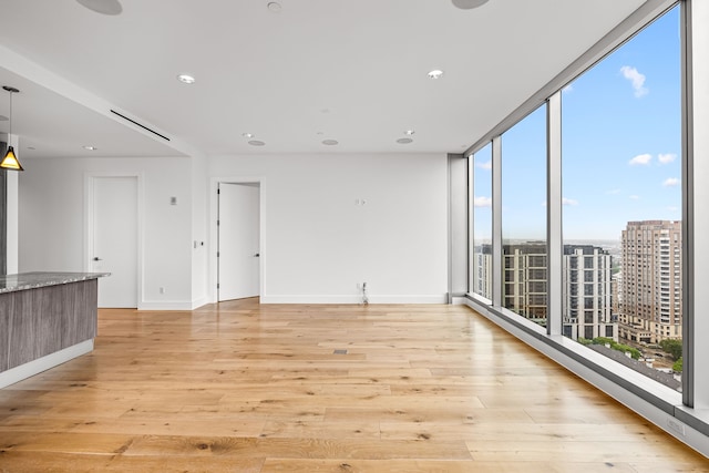 spare room with recessed lighting, light wood finished floors, and baseboards