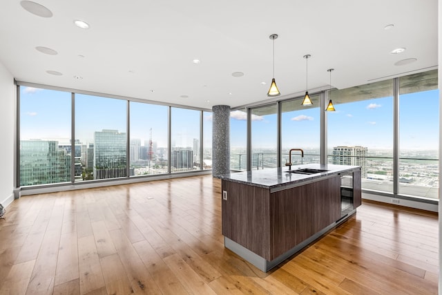 kitchen with dark brown cabinetry, open floor plan, a kitchen island with sink, modern cabinets, and a sink