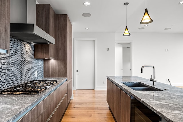 kitchen with a sink, wall chimney exhaust hood, modern cabinets, and stainless steel gas stovetop