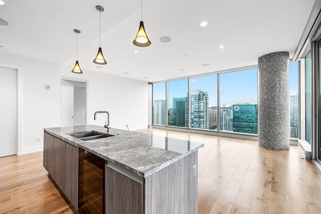 kitchen featuring modern cabinets, a sink, open floor plan, light wood-type flooring, and beverage cooler