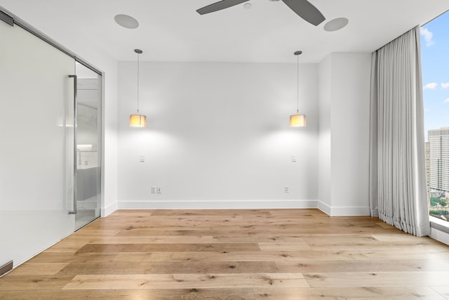 unfurnished room with light wood finished floors, ceiling fan, and baseboards