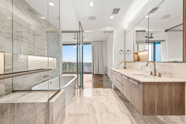 bathroom featuring double vanity, a soaking tub, recessed lighting, visible vents, and a sink