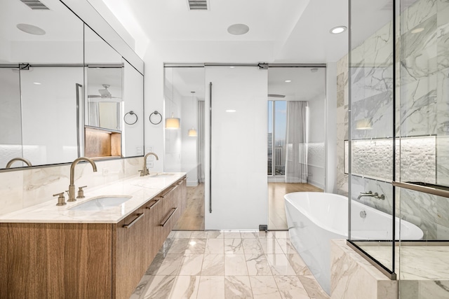 bathroom with double vanity, a soaking tub, marble finish floor, and a sink