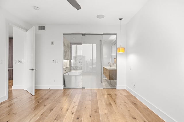 unfurnished bedroom with ensuite bathroom, light wood-type flooring, visible vents, a sink, and baseboards