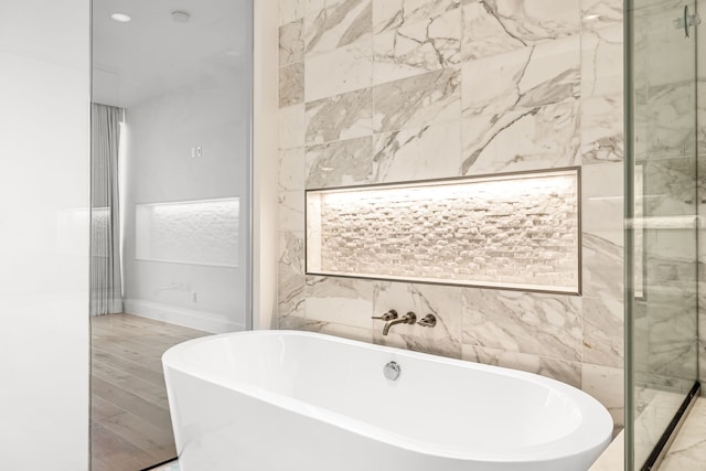 full bath with a shower stall, a freestanding bath, and baseboards