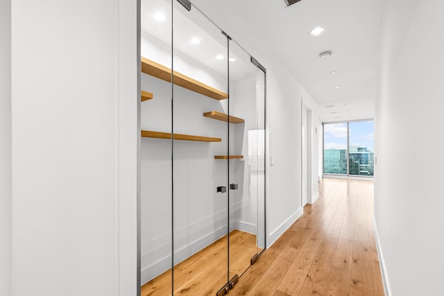hallway with light wood-style floors, baseboards, and recessed lighting