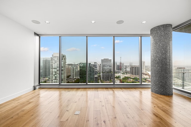 empty room featuring a view of city, wood-type flooring, and plenty of natural light