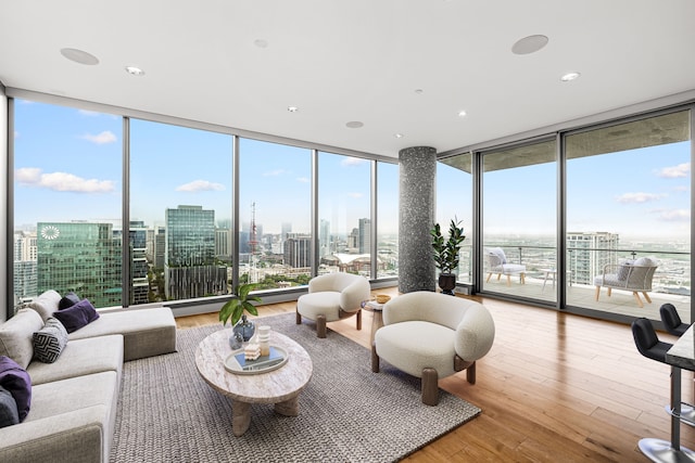 living area with a city view, a wealth of natural light, expansive windows, and hardwood / wood-style flooring