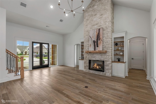 386 Newburn Ln, Shreveport, LA 71106 - unfurnished living room featuring wood finished floors, high vaulted ceiling, visible vents, a stone fireplace, and a chandelier