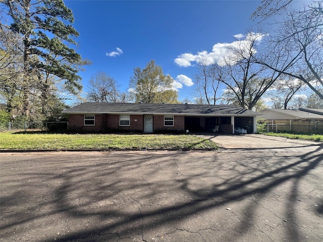 single story home with driveway, a front lawn, an attached carport, brick siding, and fence