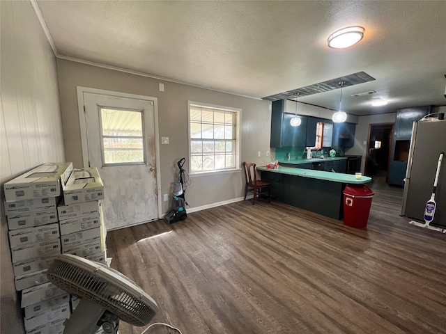 kitchen with pendant lighting, a peninsula, a textured ceiling, dark wood-style flooring, and baseboards