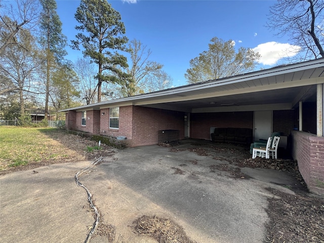 view of property exterior with a carport, brick siding, and driveway
