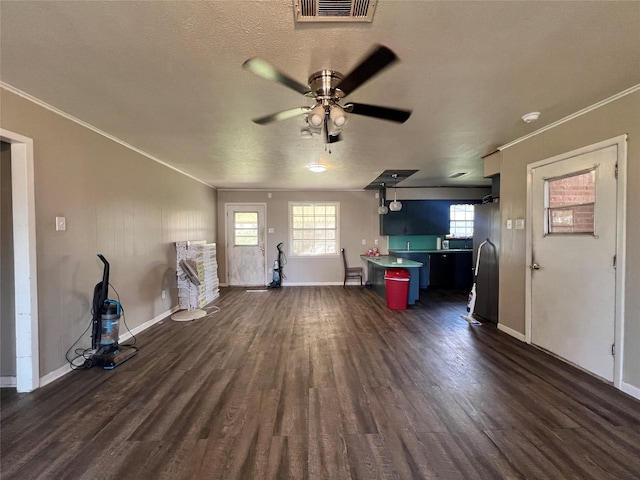 unfurnished living room featuring visible vents, ornamental molding, and dark wood finished floors