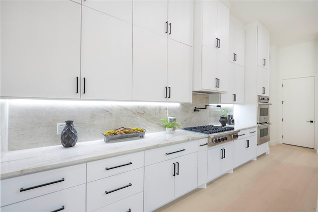 4218 Bonham St, Dallas, TX 75229 - kitchen featuring stainless steel appliances, tasteful backsplash, light stone countertops, white cabinetry, and light wood-style floors
