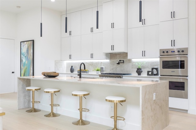 4218 Bonham St, Dallas, TX 75229 - kitchen featuring double oven, a sink, tasteful backsplash, a breakfast bar, and a kitchen island with sink