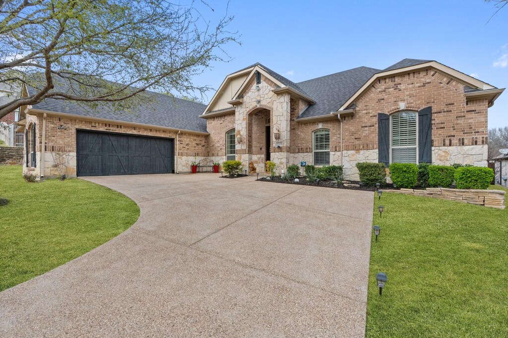 2318 Highgate Dr, Mckinney, TX 75070 - french provincial home with an attached garage, stone siding, a front lawn, driveway, and roof with shingles