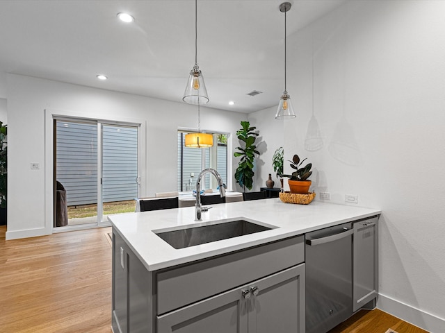 kitchen featuring gray cabinetry, dishwasher, a sink, and light wood-style flooring