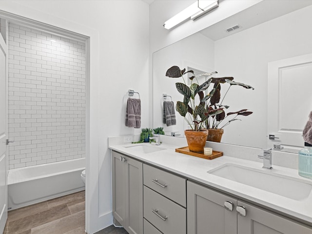 full bathroom with double vanity, visible vents, a sink, and toilet