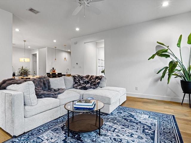 living room featuring visible vents, baseboards, ceiling fan, recessed lighting, and wood finished floors