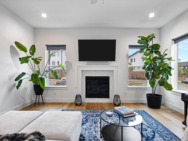 living area with recessed lighting, a tile fireplace, baseboards, and wood finished floors