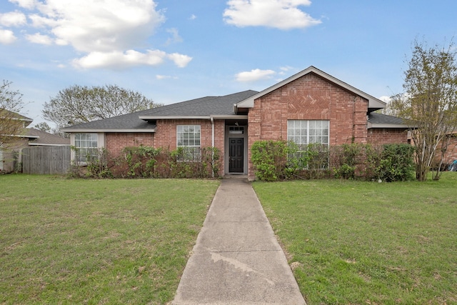 single story home with a shingled roof, a front lawn, and brick siding