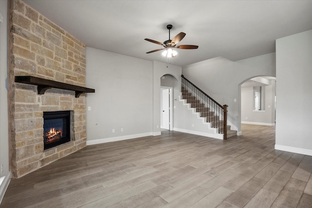 5010 Huffines Blvd, Royse City, TX 75189 - unfurnished living room featuring arched walkways, a stone fireplace, wood finished floors, and ceiling fan