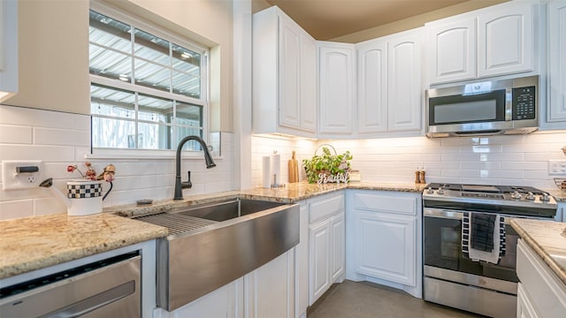 kitchen with a sink, appliances with stainless steel finishes, decorative backsplash, and white cabinetry