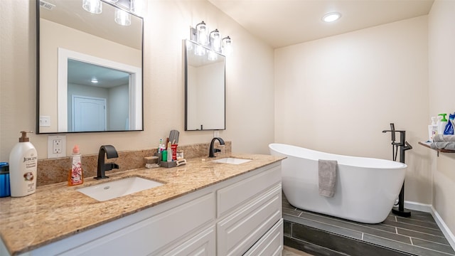 full bathroom with double vanity, recessed lighting, a sink, and a soaking tub