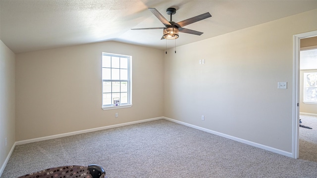 carpeted empty room with baseboards, ceiling fan, and vaulted ceiling