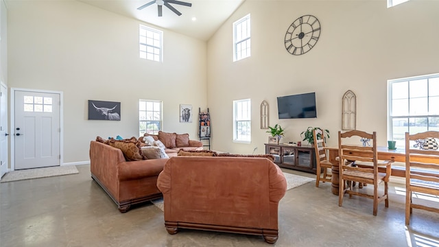living room featuring a ceiling fan, high vaulted ceiling, a wealth of natural light, and finished concrete floors