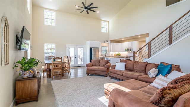 living room with a healthy amount of sunlight, high vaulted ceiling, a ceiling fan, and concrete floors