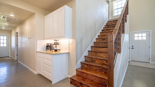 stairs with recessed lighting, baseboards, visible vents, and finished concrete floors