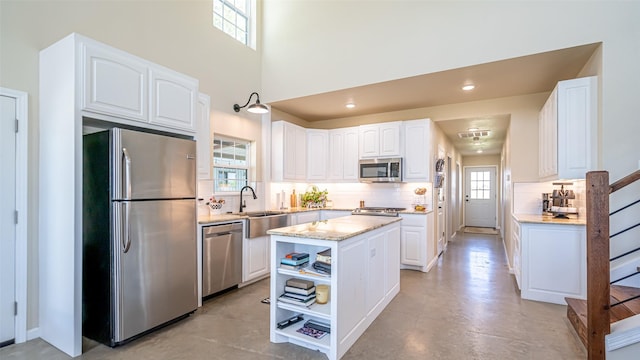 kitchen featuring tasteful backsplash, light stone countertops, stainless steel appliances, and white cabinetry