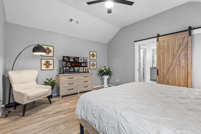 bedroom with visible vents, baseboards, a barn door, light wood finished floors, and lofted ceiling