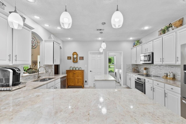 kitchen with decorative backsplash, independent washer and dryer, a sink, and appliances with stainless steel finishes