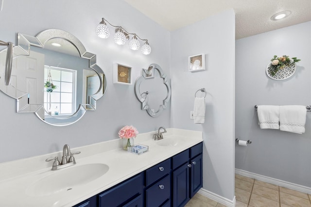full bathroom with double vanity, tile patterned floors, baseboards, and a sink
