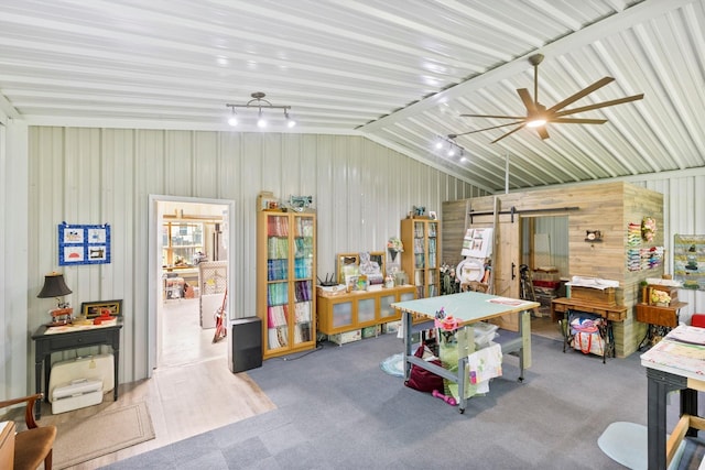 interior space featuring a barn door, lofted ceiling, a ceiling fan, and wood walls