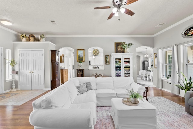 living area featuring arched walkways, visible vents, and a ceiling fan