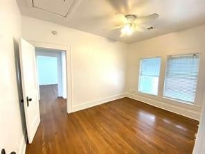 empty room with ceiling fan, attic access, baseboards, and dark wood finished floors