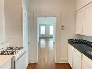 kitchen with white cabinetry, dark wood-style flooring, and white appliances
